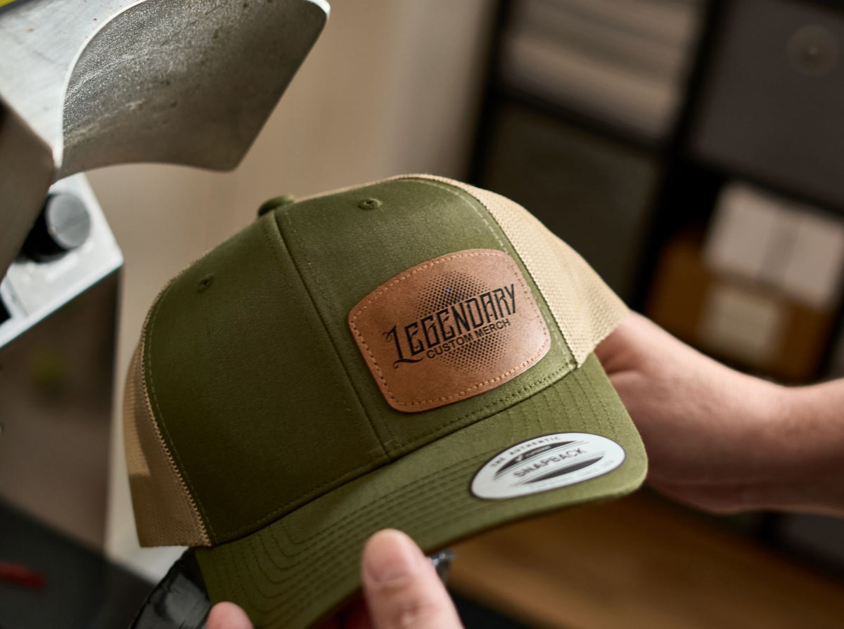 Green and beige cap with a leather patch labeled 'Legendary' held by a person.